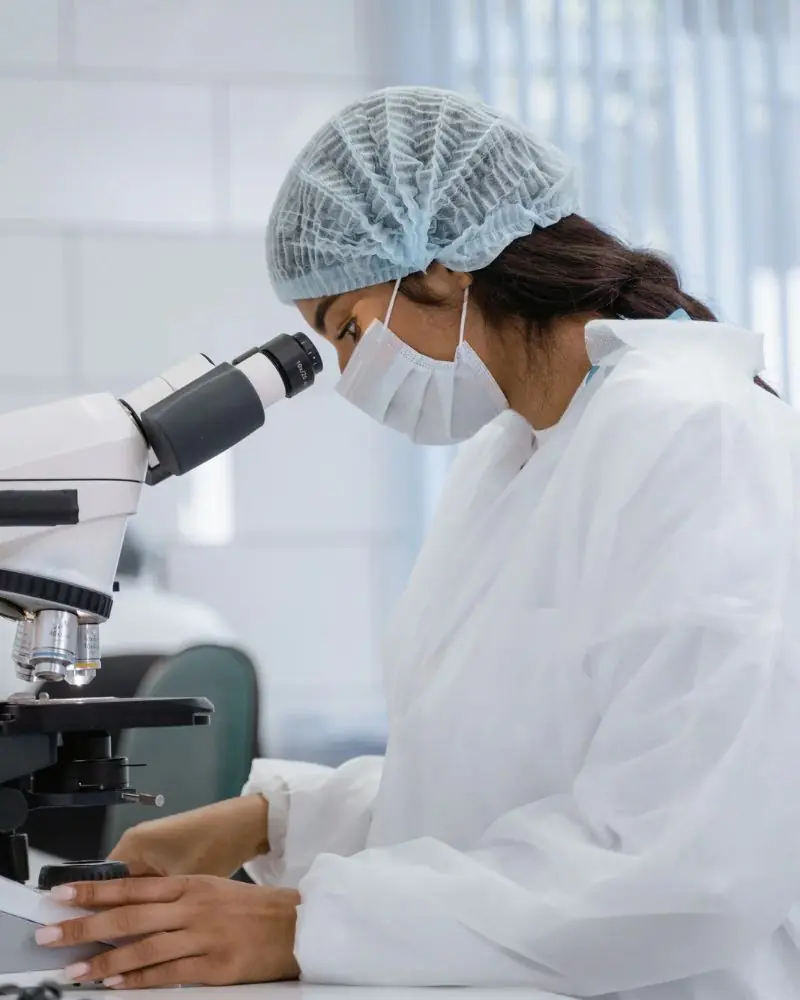 Scientist examining microscope in lab.