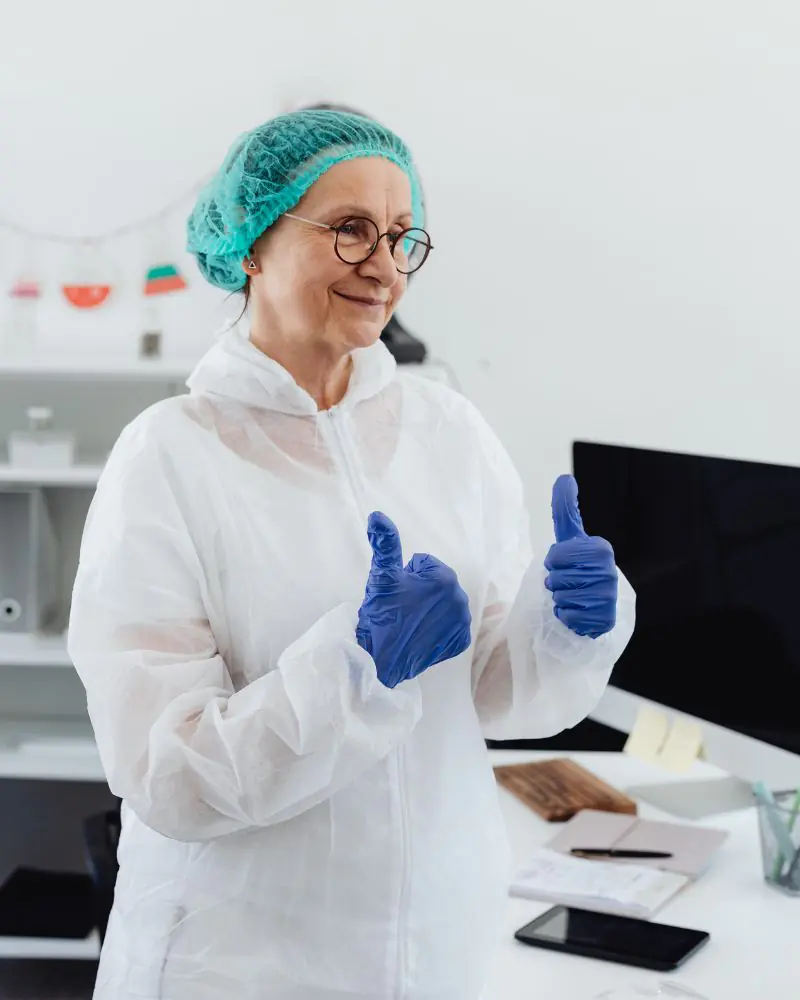 Smiling scientist gives thumbs up in lab.