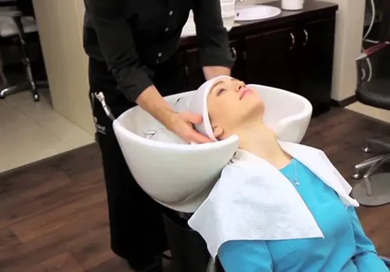 Woman receiving hair wash at salon sink.