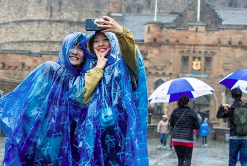 Tourists in rain ponchos taking selfie at castle