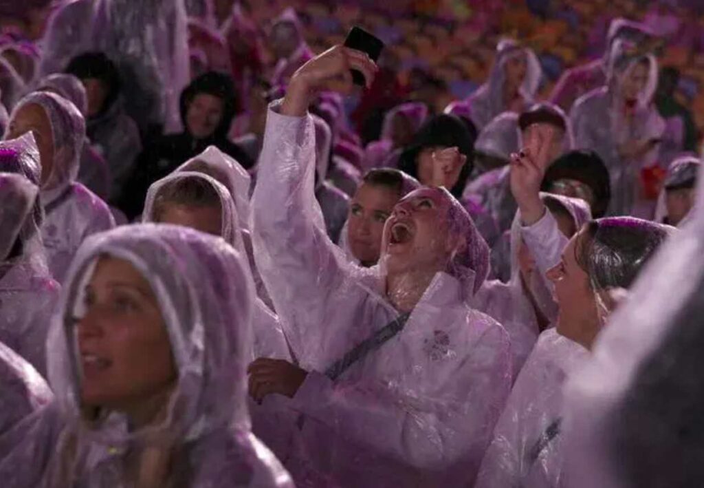 People in raincoats enjoying and taking selfies in rain.