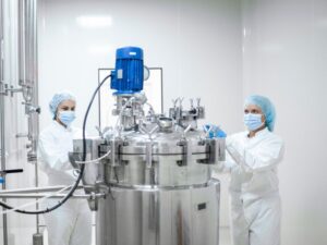 Scientists in lab coats operating a bioreactor.