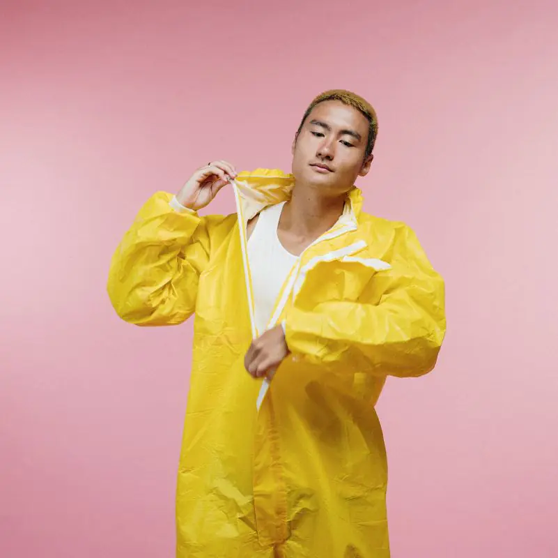 Person in yellow raincoat against pink background