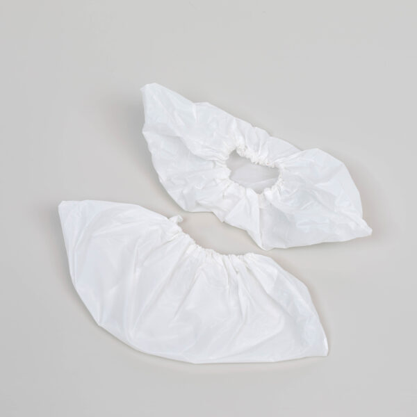 Two white disposable shoe covers on gray background.