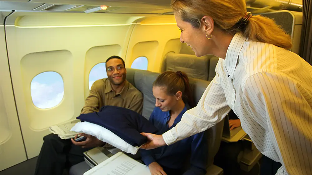 Flight attendant serving passengers onboard aircraft.