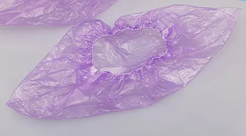 Purple disposable shoe covers on white background.