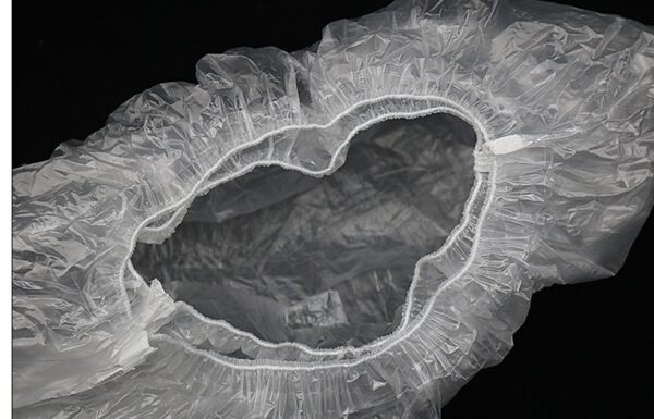 Transparent disposable shoe cover on black background.