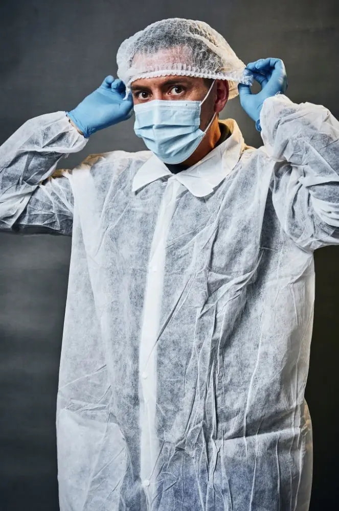 Person in protective clothing adjusting hairnet