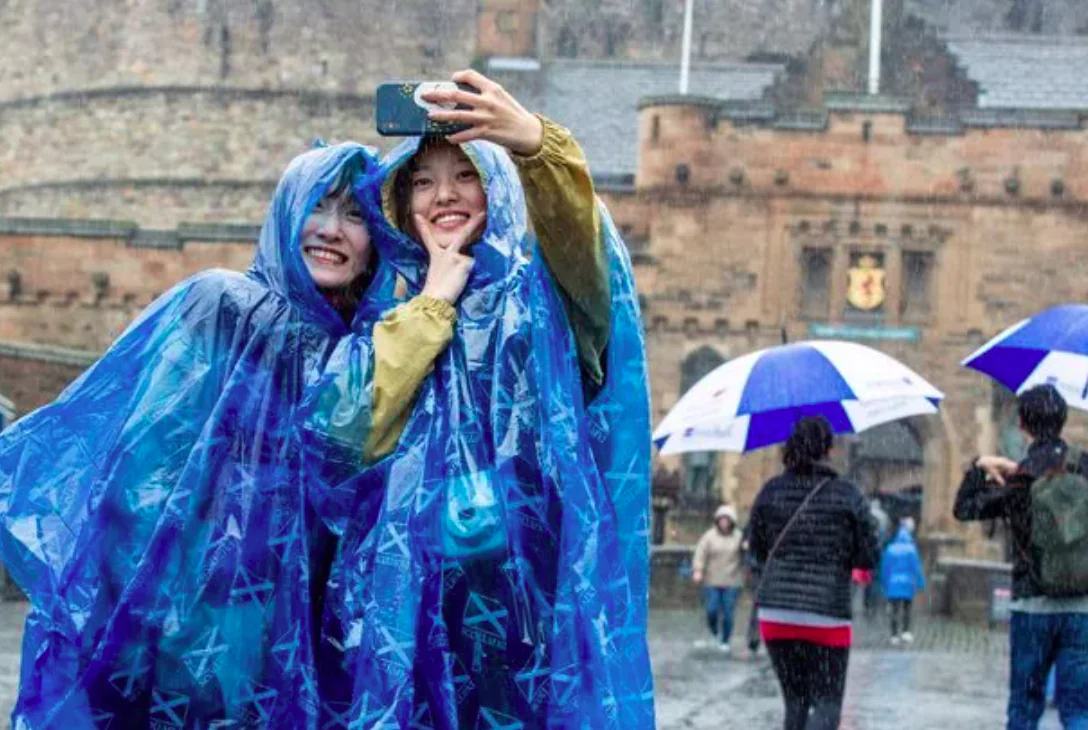 People in rain ponchos taking selfie in rain