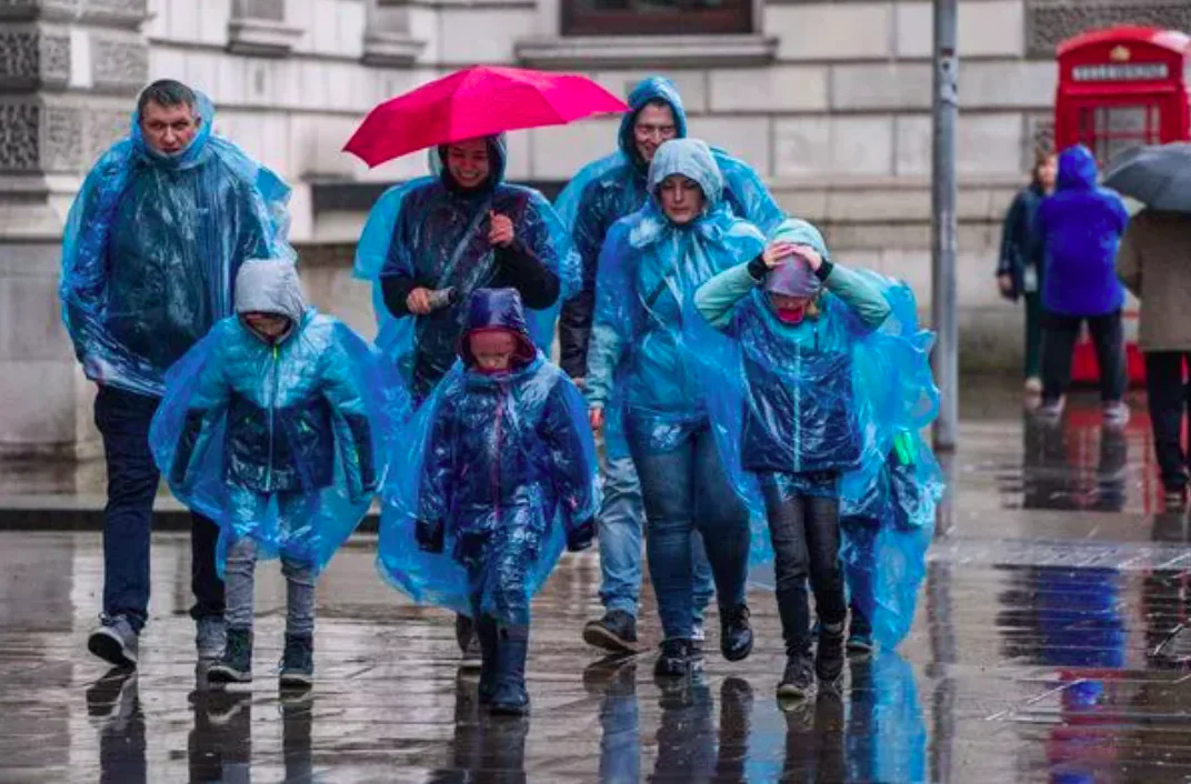 Group walking in rain with ponchos and umbrellas