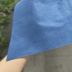 Person holding blue fabric cloth outdoors.