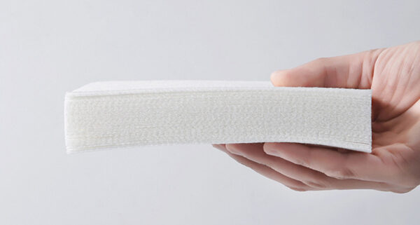 Hand holding stack of white paper napkins