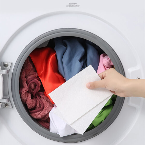 Hand placing laundry color absorber in washer.